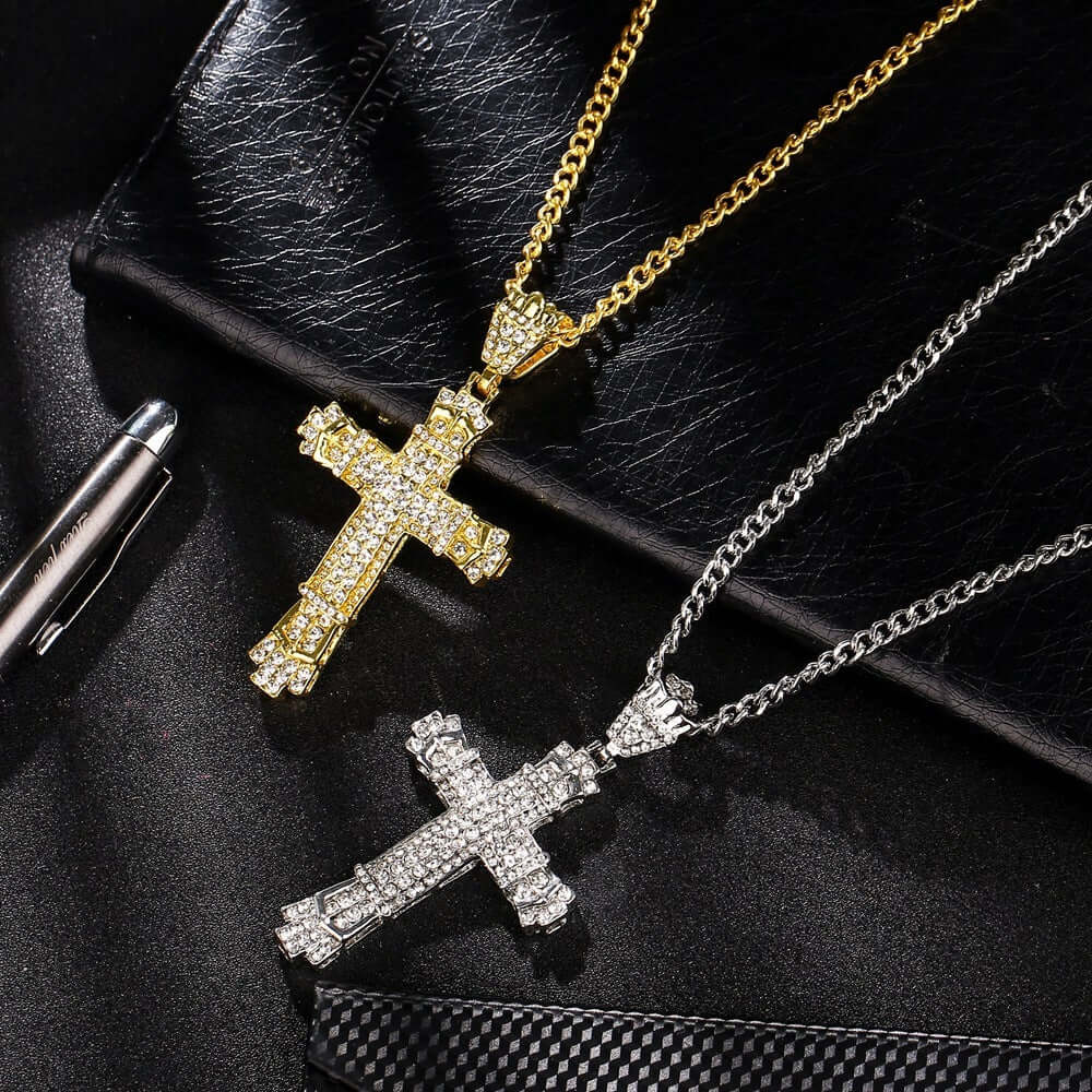 Gold and silver iced cross necklaces on black leather background, showcasing luxury and style.